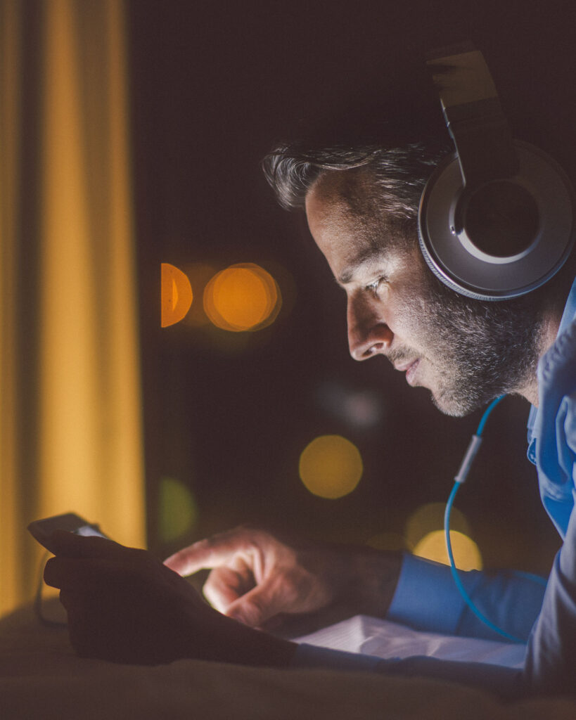 Man wearing headphones and using tablet pc in the evening