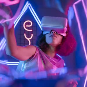 Woman wearing virtual reality simulator in glowing neon light room