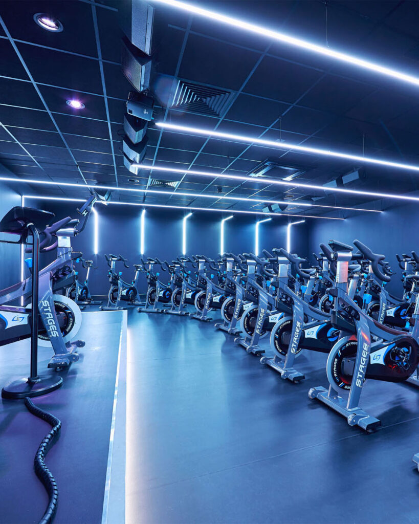 A fitness studio class that shows exercise bikes and immersive fitness technology such as audio visual solutions.