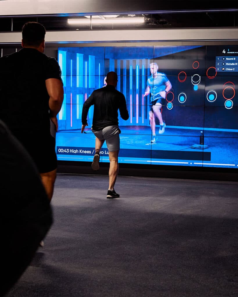 Video wall being creating an immersive fitness experience with audio visual solutions being used in fitness studio class.